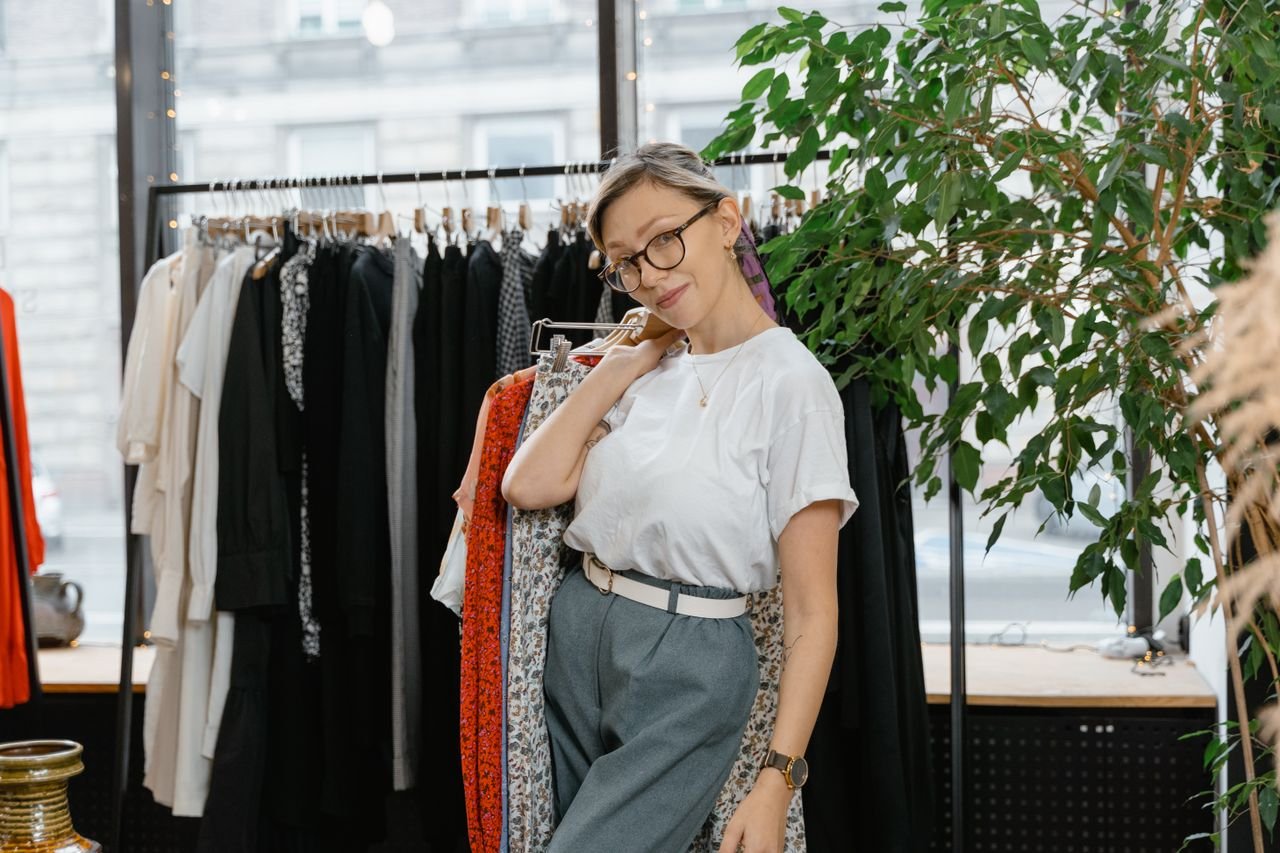Home Young woman posing casually in a fashionable boutique with trendy clothing on display.