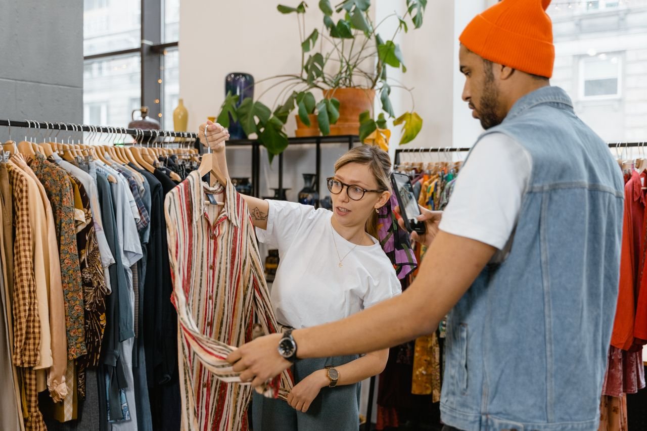 About A woman helps a man choose a shirt in a modern clothing store.